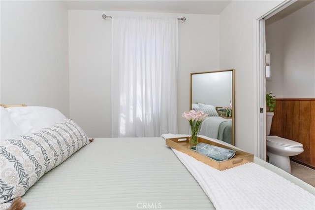 bedroom featuring wooden walls and wainscoting