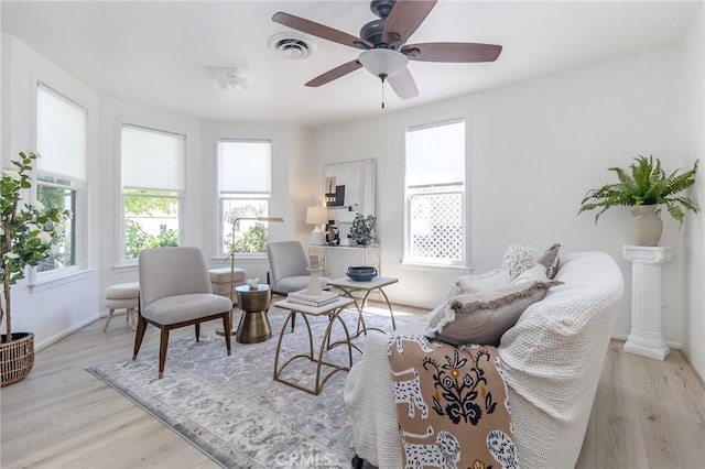 living room featuring visible vents, light wood-style flooring, and plenty of natural light