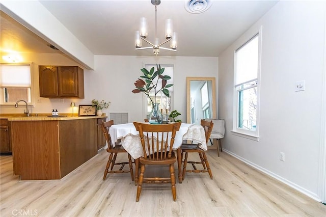 dining area featuring light wood-style flooring, baseboards, an inviting chandelier, and visible vents
