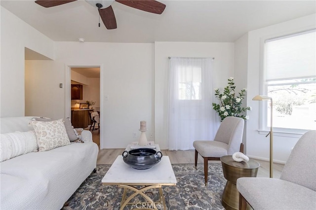 living area with a ceiling fan, wood finished floors, and a healthy amount of sunlight