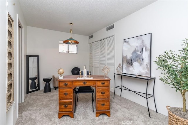 office space featuring visible vents, light carpet, and a textured ceiling