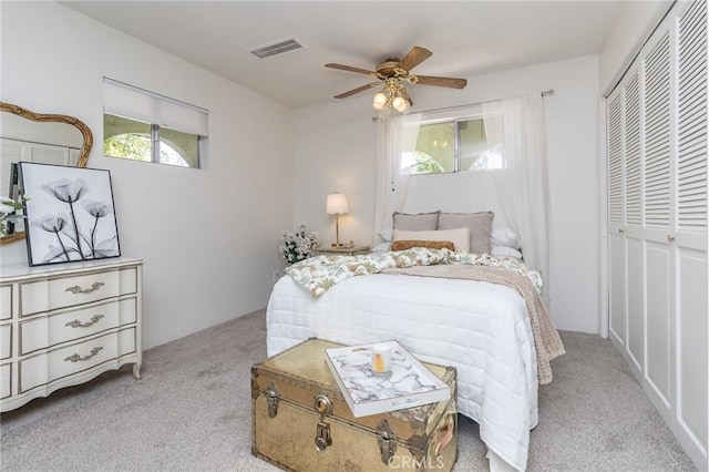 carpeted bedroom featuring visible vents, ceiling fan, and a closet