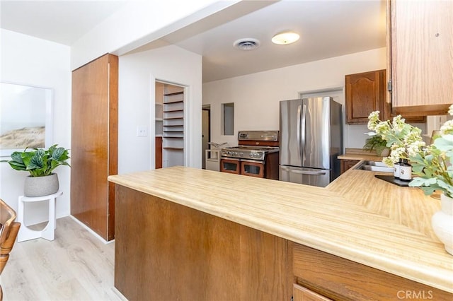 kitchen with visible vents, light countertops, light wood-type flooring, a peninsula, and stainless steel appliances