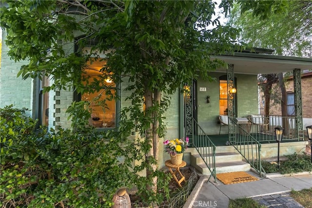 entrance to property featuring brick siding and a porch