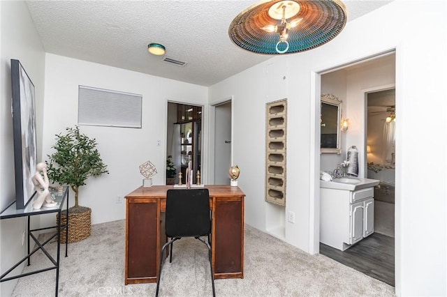 carpeted office space featuring a sink, visible vents, a ceiling fan, and a textured ceiling