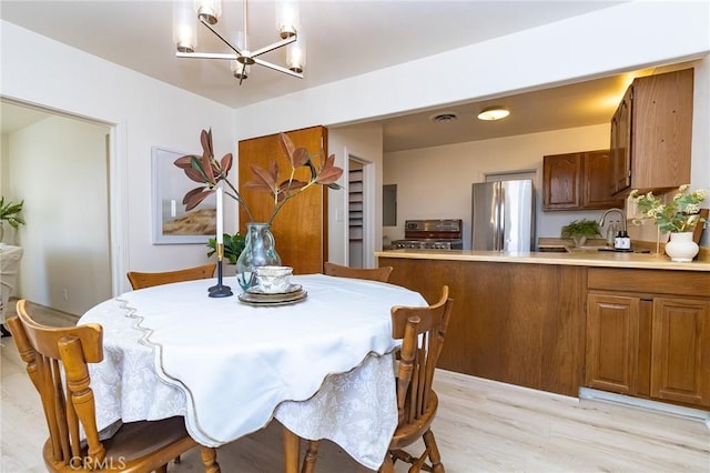 dining space featuring light wood-style flooring, an inviting chandelier, and visible vents
