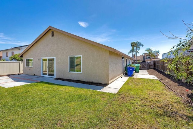 back of house featuring a lawn, a patio area, a fenced backyard, and stucco siding