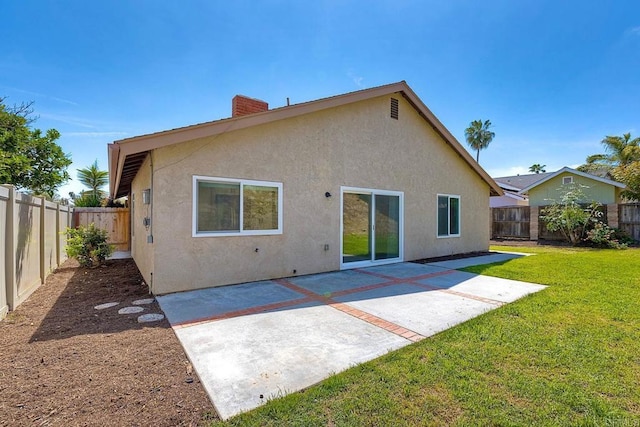 rear view of property featuring a yard, a fenced backyard, a chimney, and stucco siding