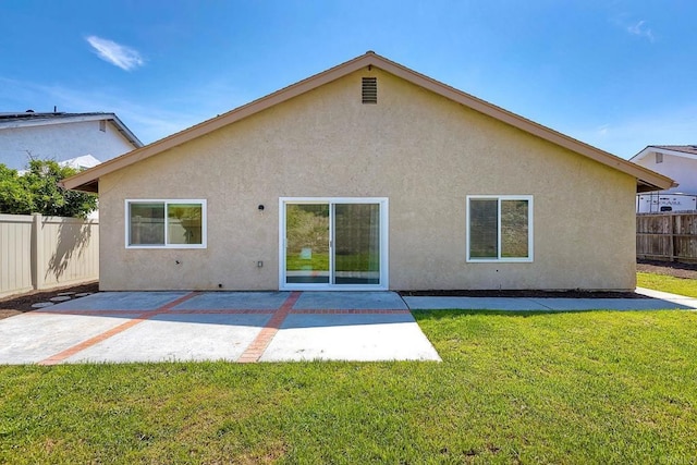 back of property with stucco siding, a patio area, a lawn, and fence