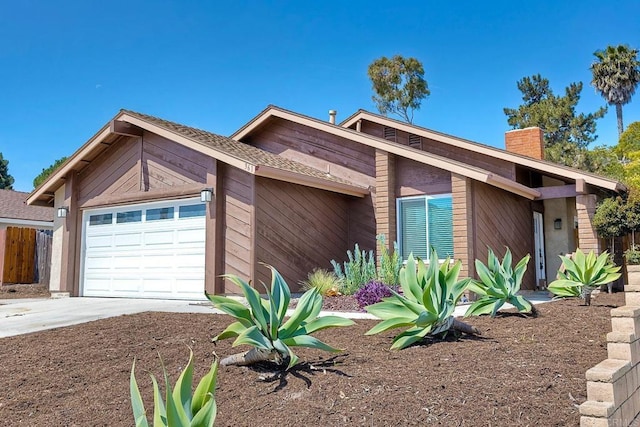 view of front of property with an attached garage, a chimney, fence, and driveway