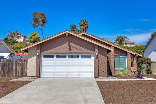 view of front facade with a garage, stucco siding, driveway, and fence