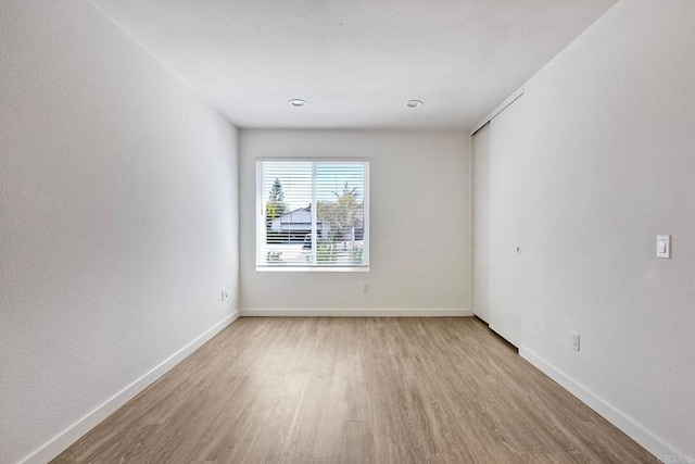 spare room featuring baseboards and light wood finished floors