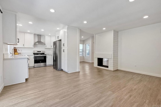 unfurnished living room featuring a sink, light wood-style floors, a fireplace, baseboards, and recessed lighting