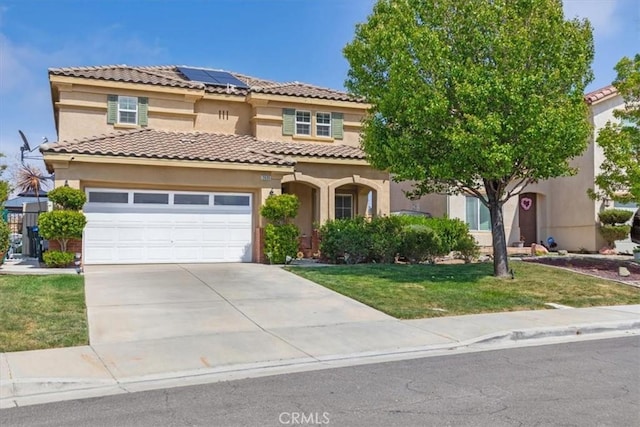 mediterranean / spanish house with a tiled roof, solar panels, driveway, a front yard, and stucco siding