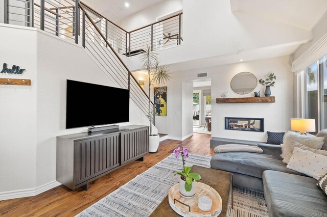 1024 Cottage Way, Encinitas, CA 92024 - living area featuring stairs, wood finished floors, baseboards, a high ceiling, and a glass covered fireplace
