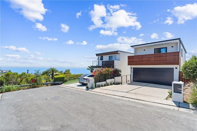 contemporary home featuring a balcony, driveway, stucco siding, and an attached garage
