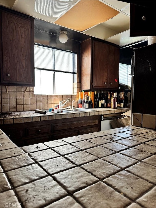 kitchen featuring tile counters, backsplash, plenty of natural light, and dark brown cabinetry
