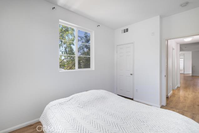 bedroom with baseboards, visible vents, and wood finished floors