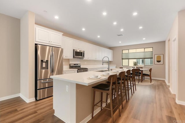 1771 Laurelwood Way, Oceanside, CA 92056 - kitchen featuring stainless steel appliances, a center island with sink, light wood-type flooring, a kitchen bar, and white cabinetry