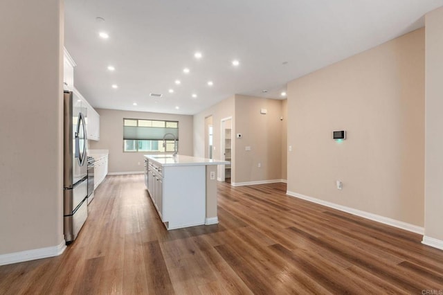1771 Laurelwood Way, Oceanside, CA 92056 - kitchen with stainless steel fridge, white cabinets, a kitchen island with sink, wood finished floors, and recessed lighting