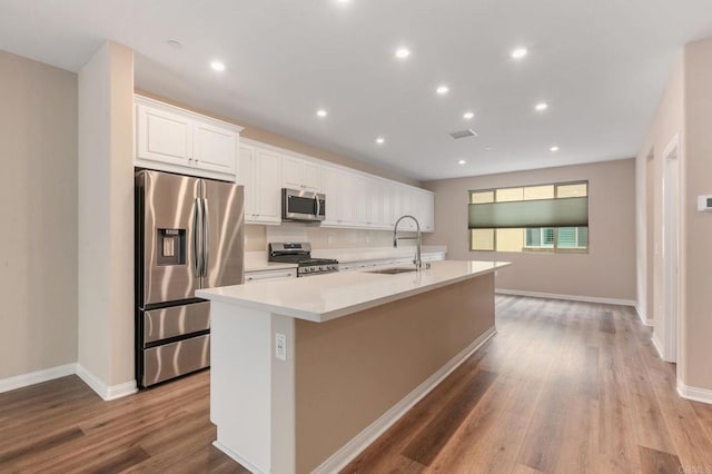 1771 Laurelwood Way, Oceanside, CA 92056 - kitchen with stainless steel appliances, an island with sink, white cabinets, wood finished floors, and recessed lighting