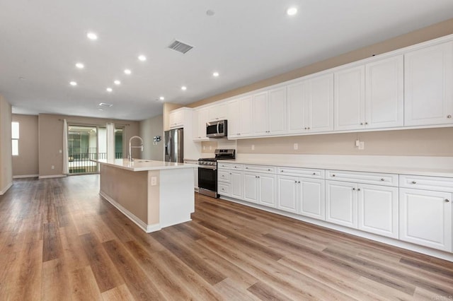 1771 Laurelwood Way, Oceanside, CA 92056 - kitchen with appliances with stainless steel finishes, white cabinetry, light wood-style flooring, an island with sink, and light countertops