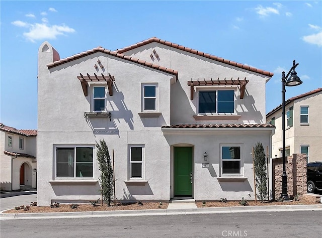 mediterranean / spanish home featuring a tiled roof and stucco siding