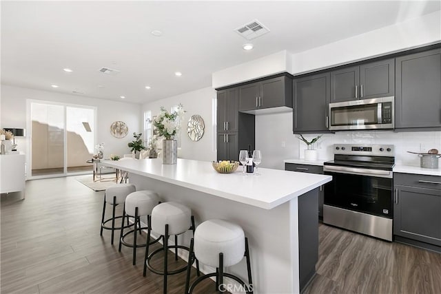 kitchen featuring appliances with stainless steel finishes, light countertops, dark wood finished floors, and visible vents