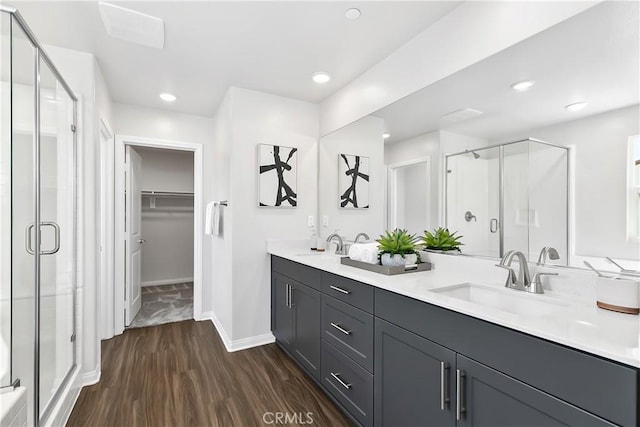 full bathroom featuring a sink, a shower stall, and wood finished floors