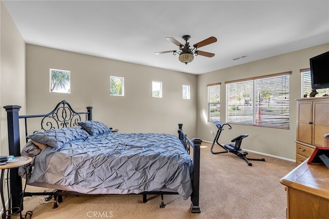 carpeted bedroom with visible vents, multiple windows, baseboards, and ceiling fan