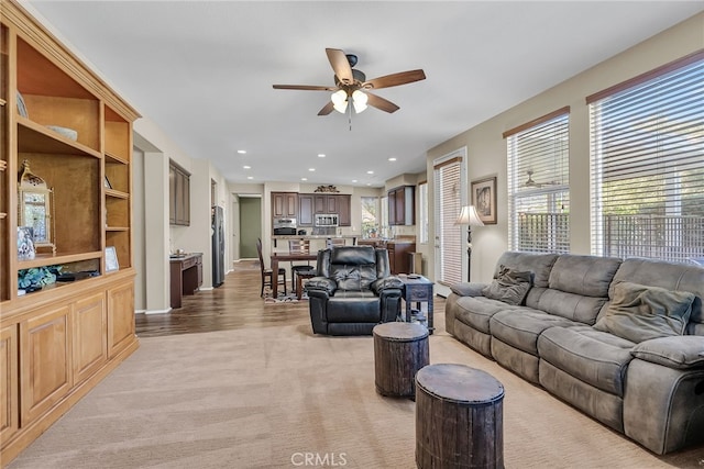 living room with light carpet, a ceiling fan, and recessed lighting