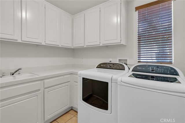 washroom with light tile patterned flooring, washer and dryer, a sink, and cabinet space
