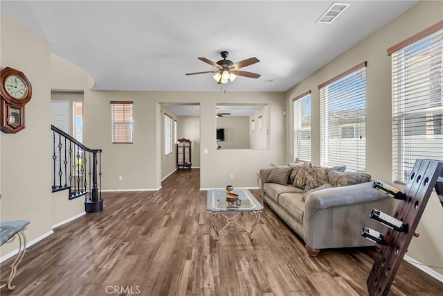 living area featuring ceiling fan, visible vents, stairway, wood finished floors, and baseboards
