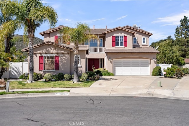 view of front of property featuring a balcony, stucco siding, driveway, a garage, and fence