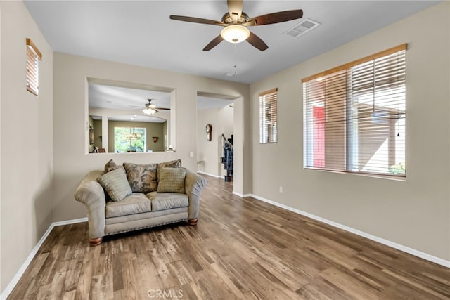 living room featuring wood finished floors, baseboards, a ceiling fan, and visible vents