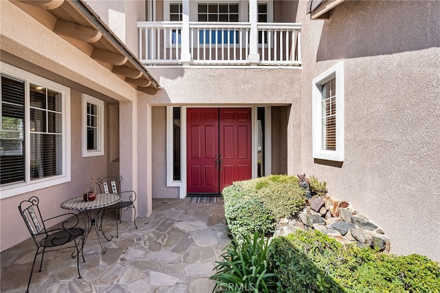 property entrance with a balcony and stucco siding