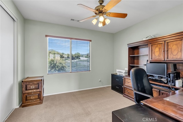 office space with visible vents, baseboards, a ceiling fan, and light colored carpet