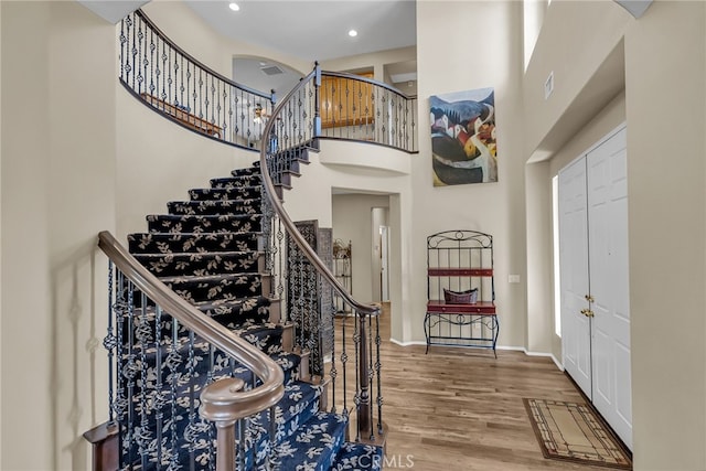 entryway featuring wood finished floors, a towering ceiling, stairway, and recessed lighting