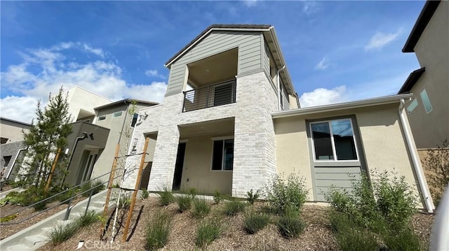230 Sora, Irvine, CA 92618 - view of property exterior featuring stucco siding, stone siding, and a balcony