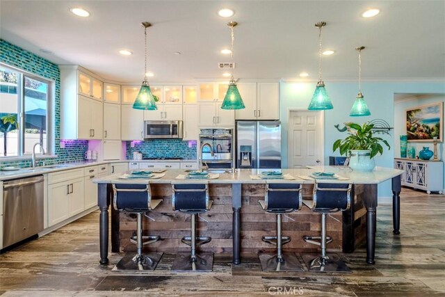 25279 Spur Branch Pl, Menifee, CA 92584 - kitchen with stainless steel appliances, tasteful backsplash, white cabinetry, a kitchen bar, and crown molding