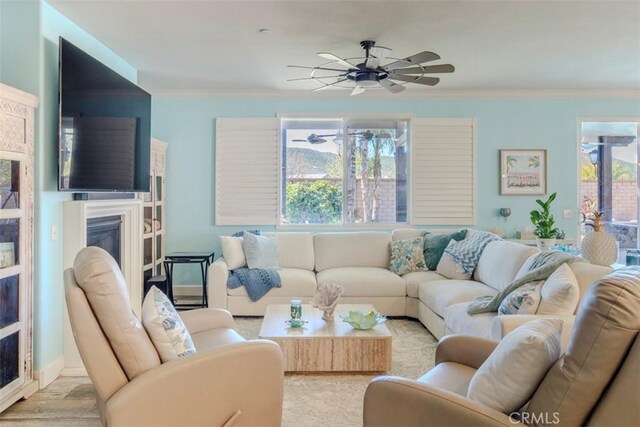 25279 Spur Branch Pl, Menifee, CA 92584 - living area featuring crown molding, a glass covered fireplace, healthy amount of natural light, ceiling fan, and wood finished floors