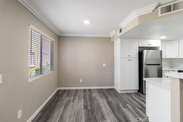 kitchen featuring visible vents, light countertops, freestanding refrigerator, and ornamental molding