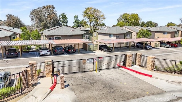 view of road featuring sidewalks, curbs, a gated entry, and a residential view