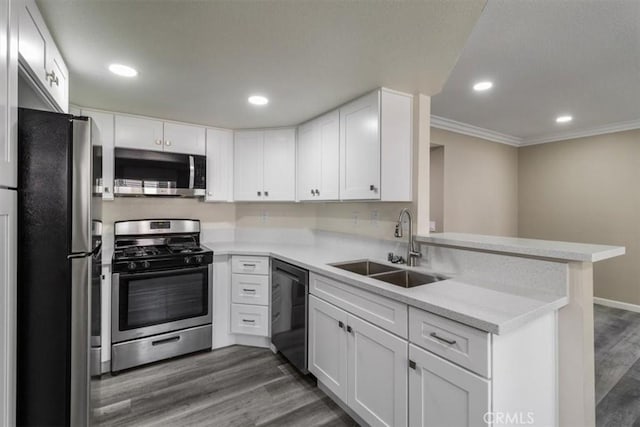 kitchen with ornamental molding, appliances with stainless steel finishes, wood finished floors, light countertops, and a sink