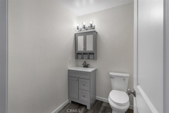 bathroom featuring toilet, wood finished floors, vanity, and baseboards