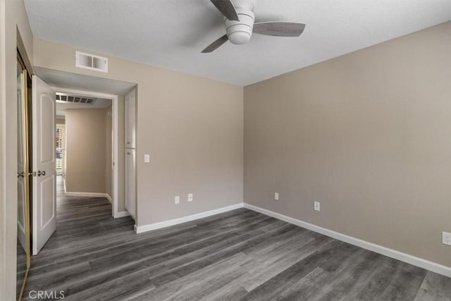 unfurnished room featuring visible vents, dark wood-style flooring, and a ceiling fan