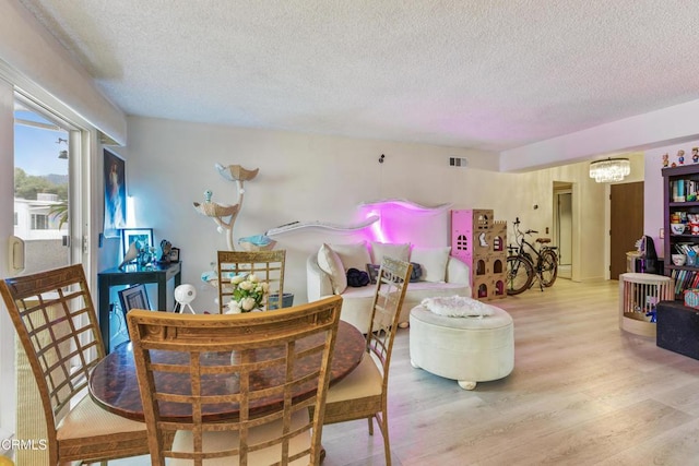dining area with an inviting chandelier, wood finished floors, a textured ceiling, and visible vents