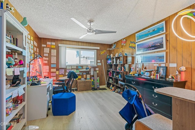 office area featuring wood finished floors, wood walls, a textured ceiling, and ceiling fan
