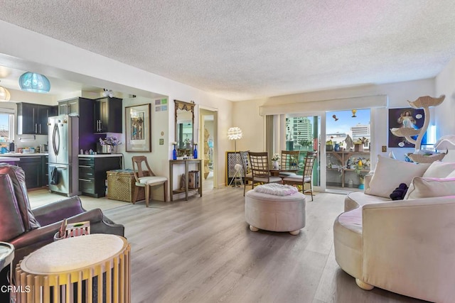 living room with plenty of natural light, a textured ceiling, and light wood-style flooring
