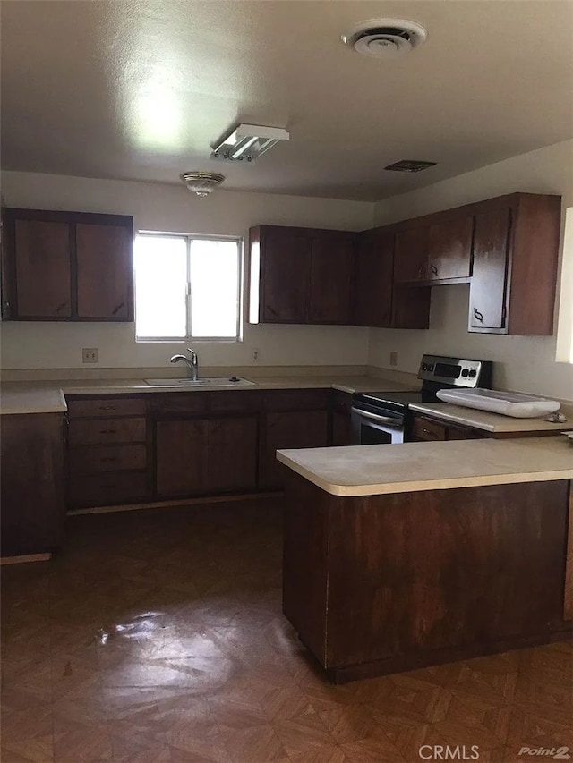 kitchen with stainless steel electric stove, dark brown cabinets, visible vents, light countertops, and a sink